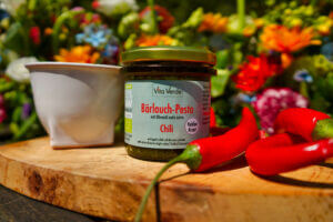 Bio Rohkost Bärlauch Chili Pesto im Glas mit Chili auf Brett