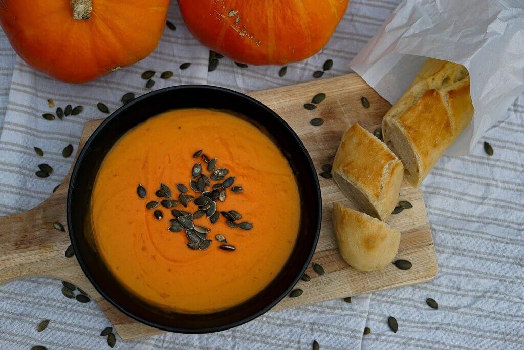 Rezeptbild fertige Kürbis Suppe mit Vita Verde Bio Orangenöl Kürbis Suppe mit Bio Orangenöl fertig in Schüssel auf Tisch mit Brot